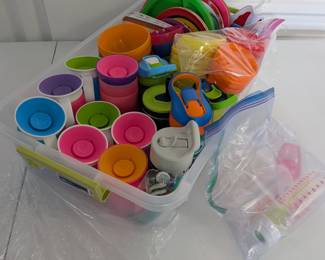 A comprehensive and colorful collection of durable plastic dining ware, perfect for busy preschools, homeschools, or large families! This extensive lot includes a generous assortment of children's plates, bowls, regular cups, various sippy cups/training cups, and baby bottles. All are ready for mealtime, snacks, and drink service. Comes conveniently packed in a large clear storage bin.  Cleaned & Ready for Use