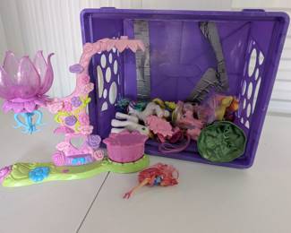 Dive into imaginative adventures with this fantastic collection of My Little Pony figures and playset pieces! This large lot includes multiple My Little Pony figures, a beautiful multi-piece floral-themed playset with a large translucent flower, and other accessories for hours of creative play. All contained in a convenient purple storage crate.