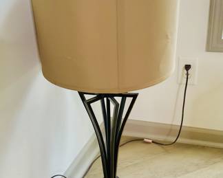 Beautiful table lamps have a dark finish with copper or brass accents that exemplifies the opulent and glamorous aesthetic. The streamlined form with stylized base compliments the light colors of the room.