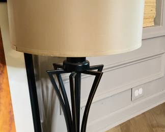 Beautiful table lamps have a dark finish with copper or brass accents that exemplifies the opulent and glamorous aesthetic. The streamlined form with stylized base compliments the light colors of the room.