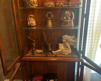 Snow globes and music boxes in a lighted curio.