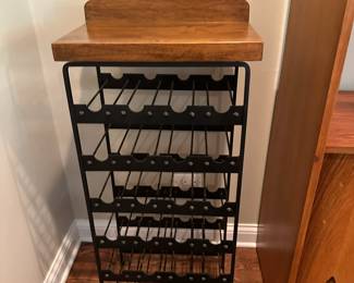 Wrought iron wine rack with wooden top.
