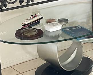 Contemporary Coffee Table with Oval top Glass , Swing out Glass piece mounted on curved metal,  mounted on Black Base. 