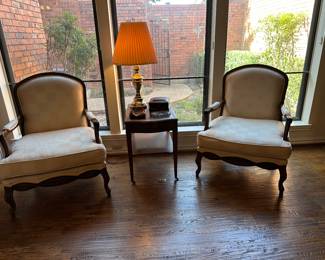 Gorgeous pair of cream colored arm chairs separated by an antique federal style leather top side table on casters and accented  with a gorgeous mid-century modern brass lamp. 