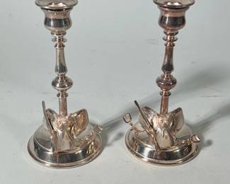 (2pc) English silver plate fox hunting candlesticks | Design on base features a fox on a saddle with stirrup and shotgun - h. 8 x w. 4 x l. 4 x d. 4 in
