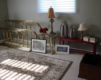 Brass bed frame, small  red bench, decorative items and rug.