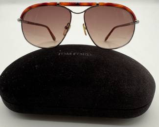 Tom Ford High Fashion "Russell" Sunglasses. These sunglasses feature a gradient lens in shades of brown. The frame has a distinctive orange and red striped pattern along the temples. The brand name 'TOM FORD' is prominently displayed on both the case and the inside of the sunglasses. The case is a dark brown color with a soft interior and also bears the 'TOM FORD' logo.