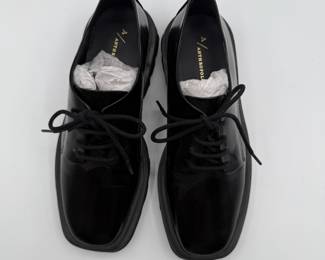 Anthropologie and made from shiny leather, featuring a rounded toe and traditional laces. The dress shoes have a thick black sole with a slightly elevated platform design.