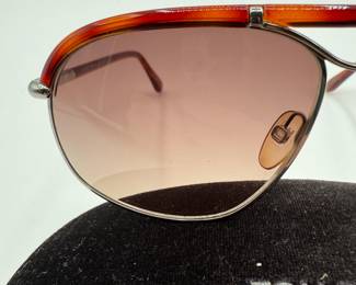 Tom Ford High Fashion "Russell" Sunglasses. These sunglasses feature a gradient lens in shades of brown. The frame has a distinctive orange and red striped pattern along the temples. The brand name 'TOM FORD' is prominently displayed on both the case and the inside of the sunglasses. The case is a dark brown color with a soft interior and also bears the 'TOM FORD' logo.