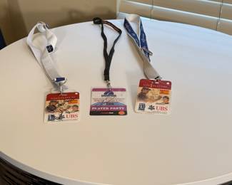 Three lanyard passes featuring a mix of red, blue, and white colors. Passes are branded with 'THE PLAYERS', 'UBS', and 'PLAYER PARTY' text. One pass is signed, dated May 10, 2009. The commemorative pin is a blue oval with a flower design, stating 'THE PLAYERS CELEBRATES MOTHERS 2009'