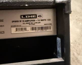 Black amplifier with a textured exterior, featuring a control panel with a variety of knobs and switches. The brand name 'LINE 6' is prominently displayed on the front. The amplifier has a rectangular shape with a mesh speaker cover. There are labels on the rear and sides with specifications and power requirements, including '120V' and '75 W Max.'