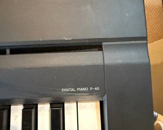 A black digital piano featuring a full keyboard with white and black keys. The brand name 'Yamaha' is clearly visible on the front of the piano. The model number 'P-45' is printed on one side. The piano has a sleek design with a sturdy black base. An adjustable black music bench is included, with a rectangular seat and a folding X-frame for support.