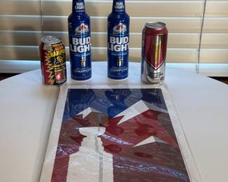 Memorabilia from the 2022 Stanley Cup Win! Two blue Bud Light bottles labeled 'Champions', one can of 'Champion', one red can with a logo. Includes a poster featuring a Stanley Cup and mountains in red and blue colors, labeled 'CHAMPIONS 2022'.
