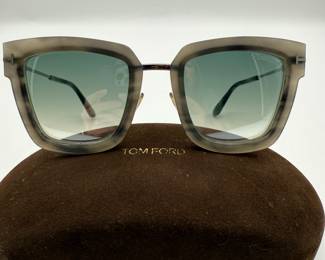 Tom Ford "Lara" sunglasses. Square-shaped sunglasses featuring a transparent gray frame and gradient lenses. The sunglasses have hard plastic temples and display the brand name 'TOM FORD' on the case and on the inside of the frame. They also include text that reads 'Lara-02 TF573 55X 52[22] 140' on the temple arm.

