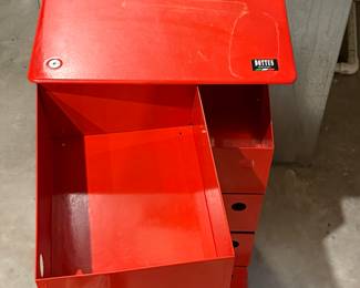 A red metal storage cabinet featuring five drawers. Each drawer has a circular handle hole. The top is smooth and flat, with visible screws securing it. The brand logo 'DOTTUS' is displayed on the top front.