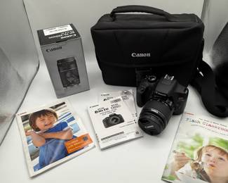 Includes a black Canon camera bag, a black Canon DSLR camera with a lens, a grey box for a Canon EF 75-300mm lens, various instruction manuals in color including a photo of a child and a cooking scene, and Canon branding on all items.