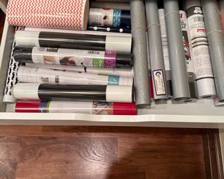 The cabinet has a smooth surface with a few visible scratches. Each drawer has a horizontal handle for easy opening. The cabinet is mounted on rolling wheels, allowing for mobility.

Also included is a large collection of Cricut supplies. 