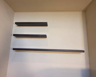 Set of three floating shelves in a dark wood finish. The shelves are rectangular in shape with a smooth surface. Each shelf varies in length and has a clean, modern design.