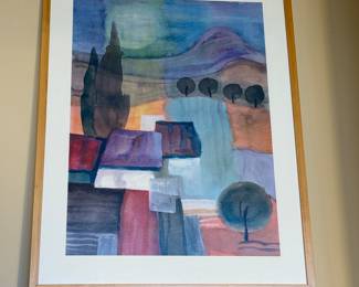 A framed artwork featuring an abstract landscape design. The piece incorporates various colors including shades of purple, blue, red, and green. It displays rounded shapes representing trees, mountains, and buildings. The frame is light wood, complementing the artwork. The back of the frame has a label from Z Gallerie indicating the item number and price.