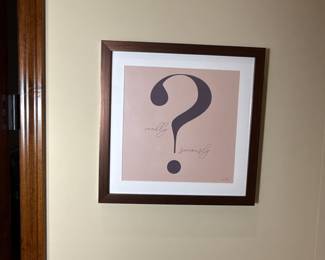 A set of four framed prints showcasing typography symbols. The first print features an ampersand '&' on a light beige background with a dark grey design. The second print displays the '@' symbol in a circular design, also in dark grey, set against the same light beige background. The third print contains an exclamation mark '!' presented in dark grey on a light beige backdrop, all framed in wooden frames with a brown finish.