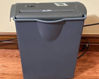 Description:
Gray rectangular paper shredder with a top opening and a label that reads 'PRIVACY GUARD'. The shredder features a control button on the front.
