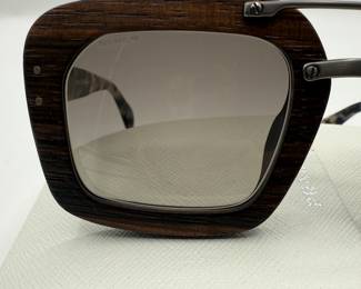 Signature Prada Style! Oversized square sunglasses featuring a dark wooden frame. The lenses are gradient and tinted, transitioning from dark to light. The temples are made of a tortoiseshell pattern, with the brand name 'PRADA' elegantly displayed. The sunglasses are accompanied by a white case.