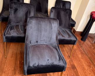This set features black velvet chairs with a sleek, modern design. The chairs have a smooth texture and are complemented by shiny gold legs. Each chair has a slightly curved back and a minimalist shape, making them ideal for contemporary decor.