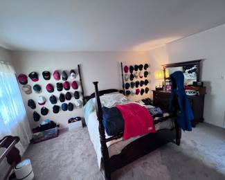Bedroom filled with beautiful antique furniture, sports hats, gloves, hats, miscellaneous bedding and quilts