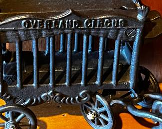 Cast Iron Toys: Several cast iron vehicles, including a circus wagon, cars, a horse-drawn carriage, and a train engine