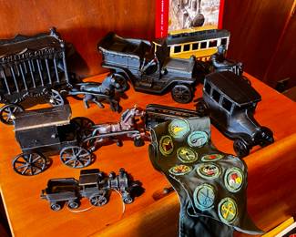 Cast Iron Toys: Several cast iron vehicles, including a circus wagon, cars, a horse-drawn carriage, and a train engine