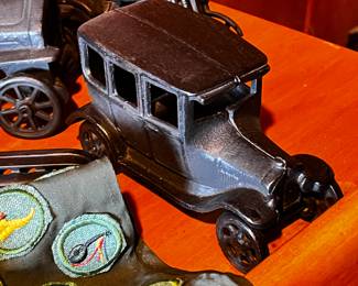 Cast Iron Toys: Several cast iron vehicles, including a circus wagon, cars, a horse-drawn carriage, and a train engine