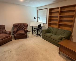 leather wingback chairs, drafting table & chair, mid-century modern end table, bookcases, cloth sofa.