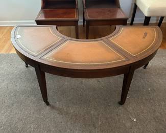 C58 - $50. Mahogany Half Circle Leather Top Coffee Table. Measures 4' x 14" deep x 16.5" tall. Each leaf adds 11.25" to each end if extended.