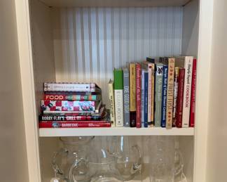 Large collection of cookbooks and serving pieces. 