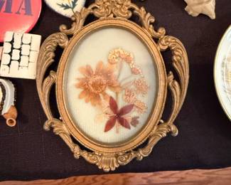 oval ornate gold colored frame with pressed flowers