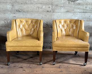 This lot features a pair of vintage club chairs with wood legs on casters. In good overall condition with minor wear as seen in photos. Each chair measures, 29” H x 25.5” W x 31” D.