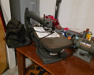 Garage table filled with electric tools.   Saws, grinders, vice even the table is for sale.