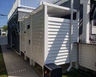Vinyl outdoor shower has a central dressing room with his & hers showers
