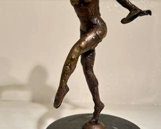 bronze sculpture of a dancer mounted on a black marble pedestal. 
