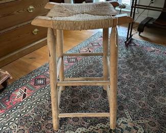 F22- $25. Wooden Rattan Woven Bar Stool. Measures 16" wide x 12" deep x 27" tall.