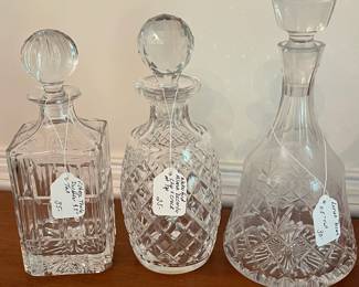 D12- (left to right) $35 Vintage Towle Decanter measuring 9.5" tall, $25 Waterford Alana Decanter with chip+crack at the top measures 10" tall, $30 Lenox Decanter measures 11.5" tall