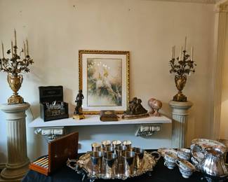 Pair of elaborate bronze urns with candle holders, terra cotta puttu, and other accessories as seen across the table laden with silver hollow ware serving pieces.