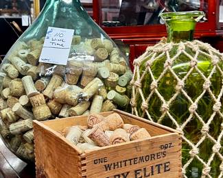 Large decorative glass vessels with wine, corks, and antique shoe polish box