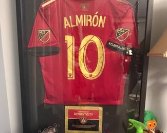 framed Atlanta United FC jersey, specifically the number 10 jersey of Miguel Almirón from the 2017 season. The jersey is signed and includes a "Certificate of Authenticity”