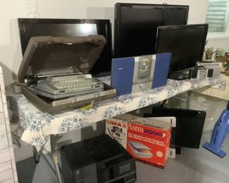 Multiple electronics.  Old typewriter, two flatscreen TVs,.  Older cd player, color scanner