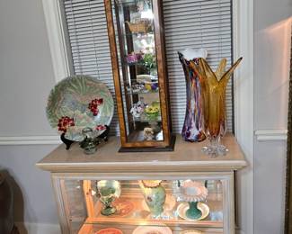 Lighted display cabinet shows off beautiful vases. On top is hand-blown glass and other collectibles.