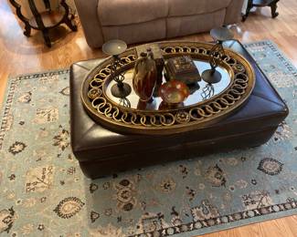Ottoman coffee table, wall mirror , candleholders, and ornate boxes, beautiful blue and black area rug.