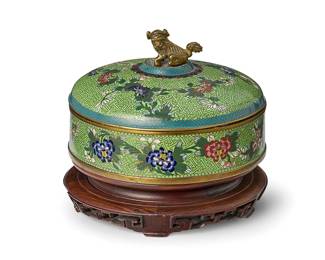 2135
A Chinese cloisonné lidded box
Circa 1900
The copper and enamel box decorated with floral motifs, the lid featuring a dog-form finial, set on a carved wood stand
Box: 5.25" H x 8.125" Dia.; Stand: 2.375" H x 8.5" Dia.
Estimate: $600 - $800