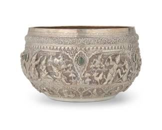 2276
A Burmese stone-mounted sterling silver bowl
1996
Marked to underside: Visit / Myanmar Year / 1996 / M.G.E. 95%
The round vessel with elaborate chased and repoussé scrolled motifs surrounding a band of haute-relief figures with inset green stone cabochons
6.75" H x 11" Dia.
55.2 gross oz. troy approximately
Estimate: $1,200 - $1,800