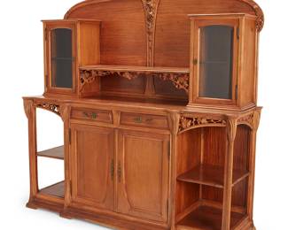 2085
A French Art Nouveau buffet
Circa 1900; Nancy, France
The buffet with carved openwork and relief grapevine accents and foliate-form brass drawer pulls, the upper unit with a central shelf flanked by glazed locking cabinets, each with a single glass shelf, the lower unit with two central drawers above two locking cabinet doors revealing a single shelf, flanked by open shelves to each side
80" H x 77.5" W x 23" D
Estimate: $800 - $1,200